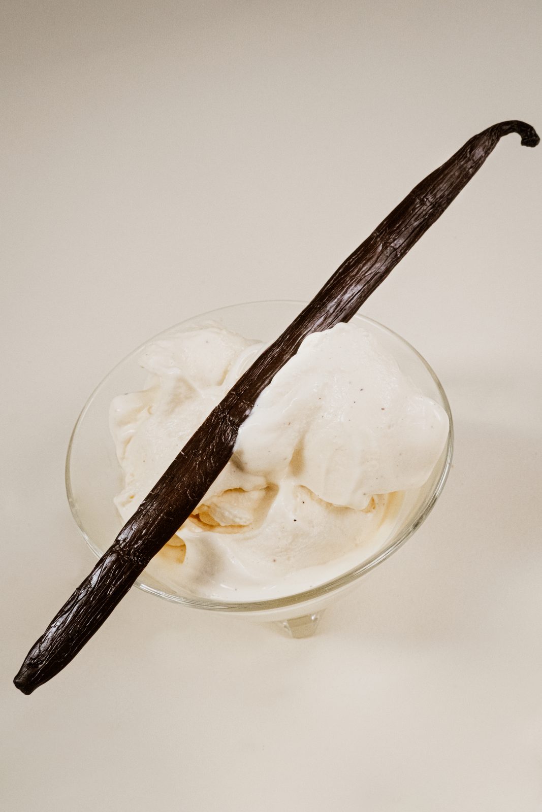 Glace à la vanille maison dans une coupe en verre avec une gousse de vanille de Madagascar